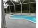Screened-in pool with light blue water surrounded by a concrete deck and lush landscaping at 8214 Tabbystone Pl, Bradenton, FL 34201