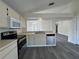 Bright kitchen with stainless steel dishwasher, grey wood floors, and white appliances at 8229 Riverboat Dr, Tampa, FL 33637