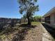 Fenced backyard with a large tree, grassy area, and access to a screened porch at 8708 Robilina Rd, Port Richey, FL 34668