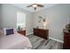 Cozy bedroom featuring a wood-look floor, ceiling fan, and a dresser with decorative lamps at 9211 Seeger Ln, Land O Lakes, FL 34638