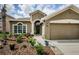 Inviting front exterior highlighting the landscaped garden, arched entryway, and attached two-car garage at 9211 Seeger Ln, Land O Lakes, FL 34638