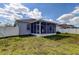 A well maintained backyard view showing the covered and screened-in patio, home exterior, and white fence at 9407 Black Thorn Loop, Land O Lakes, FL 34638