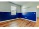 Bedroom with blue accent wall, wood-look flooring, and window providing natural light at 9407 Black Thorn Loop, Land O Lakes, FL 34638
