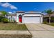 Charming single-story home with gray exterior, red front door, two car garage, and landscaped front yard at 9407 Black Thorn Loop, Land O Lakes, FL 34638