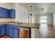 Open kitchen with stainless steel appliances and blue cabinets, and modern light fixtures at 9407 Black Thorn Loop, Land O Lakes, FL 34638