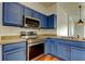 Kitchen featuring stainless steel appliances, blue cabinets, and modern light fixtures at 9407 Black Thorn Loop, Land O Lakes, FL 34638