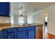 Open kitchen with stainless steel appliances and blue cabinets, and modern light fixtures at 9407 Black Thorn Loop, Land O Lakes, FL 34638