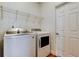 Bright laundry room with white appliances, overhead shelving, and a convenient access door at 9407 Black Thorn Loop, Land O Lakes, FL 34638