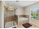 Bright bathroom featuring a glass shower, a soaking tub, and a large window at 9614 Orange Jasmine Way, Tampa, FL 33647