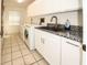 Bright laundry room with modern sink, white cabinets, granite countertops, and washer/dryer hookups at 9805 Hermosillo Dr, New Port Richey, FL 34655