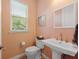 Bright half bath featuring a pedestal sink, window and peach colored walls at 112 79Th St # B, Holmes Beach, FL 34217
