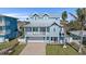 Two-story coastal home with a metal roof, a brick driveway, large garage, and a welcoming front porch at 112 79Th St # B, Holmes Beach, FL 34217