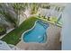 Aerial view of the kidney shaped pool in fenced backyard with lounge chairs and manicured grass at 112 79Th St # B, Holmes Beach, FL 34217