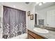 Bathroom with a patterned shower curtain and granite countertop, creating a calming space at 12857 Satin Lily Dr, Riverview, FL 33579