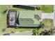 An aerial view showcasing a well-maintained home with an enclosed patio, a vibrant green roof, and verdant landscaping at 13247 Palmilla Cir, Dade City, FL 33525