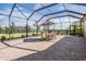 Covered outdoor patio with brick flooring, dining table and umbrella, with views of the lawn and blue sky at 13247 Palmilla Cir, Dade City, FL 33525