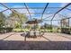Inviting screened patio with brick flooring, an outdoor dining table, and a view of the landscaped backyard at 13247 Palmilla Cir, Dade City, FL 33525