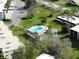 Aerial view highlighting community pool, shuffleboard courts and surrounding landscaping at 1375 Doolittle Ln # 103, Dunedin, FL 34698