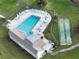 Aerial view of a community pool with lounge chairs, shuffleboard court, and beautiful landscaping at 1375 Doolittle Ln # 103, Dunedin, FL 34698