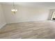 A neutral living room with wood-look tile flooring, a chandelier, and access to the screened-in lanai at 1375 Doolittle Ln # 103, Dunedin, FL 34698