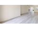 An open-concept living room features light-colored wood-look tile flooring, base molding, and neutral walls at 1375 Doolittle Ln # 103, Dunedin, FL 34698