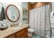 Bathroom with a granite vanity, round mirror, and a shower with a patterned curtain at 14315 Rolling Dune Rd, Lithia, FL 33547