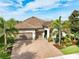 Aerial view of a single-story home with beautiful landscaping, brick driveway, tile roof, and an attached two-car garage at 14315 Rolling Dune Rd, Lithia, FL 33547