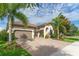 Charming home featuring a brick driveway, a two-car garage, and professionally landscaped garden with palm trees at 14315 Rolling Dune Rd, Lithia, FL 33547