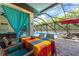 Lanai with stone flooring and brightly covered dining table with screened in pool in background at 14315 Rolling Dune Rd, Lithia, FL 33547