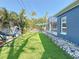A serene backyard featuring artificial turf, tropical plants, a seating area, and a screened lanai at 1859 Oklahoma Ne Ave, St Petersburg, FL 33703