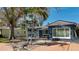 View of blue single Gathering home with palm trees, large tree, front patio, and driveway at 1859 Oklahoma Ne Ave, St Petersburg, FL 33703