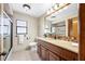 Well-lit bathroom with a granite countertop, decorative mirror, and tiled shower at 1906 Del Oro Ct, Dunedin, FL 34698