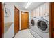 Bright laundry room features a washer and dryer, storage cabinets, tile flooring, and a utility sink at 1906 Del Oro Ct, Dunedin, FL 34698