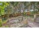 Backyard with stone terrace, wood fence, mature trees, and landscaping at 2213 Spanish Vistas Dr, Dunedin, FL 34698