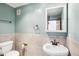 Stylish bathroom features a pedestal sink, toilet, tiled walls, and framed mirror at 2213 Spanish Vistas Dr, Dunedin, FL 34698