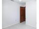 White bedroom with tile flooring and dark stained wood door that leads to a different room at 2213 Spanish Vistas Dr, Dunedin, FL 34698
