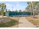 People enjoying an afternoon of tennis, with mature trees, blue sky, and lush landscaping at 300 16Th Ave, Indian Rocks Beach, FL 33785