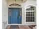 Elegant front door with sidelights and transom window, set in a textured facade with arched window at 3206 Hurley Grove Way, Valrico, FL 33596