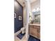 Stylish half bathroom with granite vanity, framed mirror, and blue accent wall and rug at 4206 Tour Trce, Land O Lakes, FL 34638