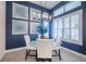 Dining area with glass table, white chairs, modern light fixture, and blue accent wall with artwork at 4206 Tour Trce, Land O Lakes, FL 34638