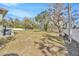 Large green backyard surrounded by mature trees and partially enclosed with a white picket fence at 4411 Culbreath Rd, Valrico, FL 33596