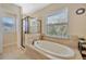 Bright bathroom with a soaking tub beneath a window and a glass-enclosed shower at 4411 Culbreath Rd, Valrico, FL 33596