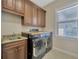 Well-equipped laundry room with modern washer/dryer and sink and granite countertops at 4411 Culbreath Rd, Valrico, FL 33596