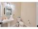 Elegant powder room with pedestal sink, round mirror, and neutral color palette at 4411 Culbreath Rd, Valrico, FL 33596