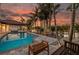A spacious backyard featuring a sparkling pool with a patio, lush palm trees, and an outdoor seating area at 4959 58Th S Ave, St Petersburg, FL 33715