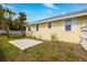 Back exterior of the home showcases yellow siding, white trim, and small garden at 718 Bay Esplanade, Clearwater Beach, FL 33767