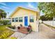 Charming yellow home with a blue door, brick steps, and well-manicured landscaping at 718 Bay Esplanade, Clearwater Beach, FL 33767