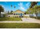 Charming yellow home with a bright blue door, landscaped front yard, and a welcoming pathway at 718 Bay Esplanade, Clearwater Beach, FL 33767