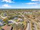 An aerial view of a residential neighborhood surrounded by lush trees with water views in the distance at 8137 Greenside Ln, Hudson, FL 34667