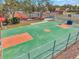 Aerial view of a fenced basketball court with a green and orange surface, surrounded by trees at 8137 Greenside Ln, Hudson, FL 34667